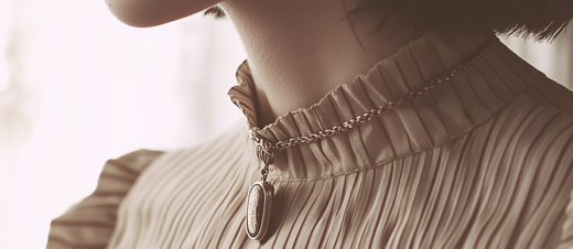 Close-up of a woman wearing a pleated top with a long necklace, with a vintage aesthetic. The colors are beige and brown, and the depth of field is shallow, creating a vintage, grainy photography look reminiscent of 35mm film.