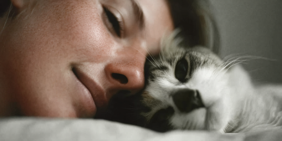 Woman and cat cuddling on a bed.